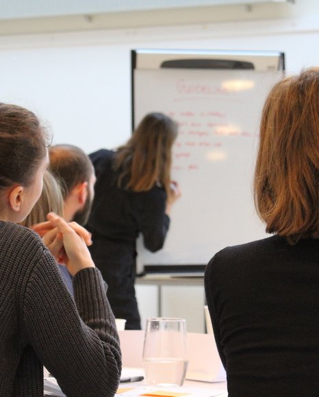 NORM underviser på whiteboard foran fire interesserede studerende fra Det Kongelige Akademi - Arkitektur, Design, Konservering